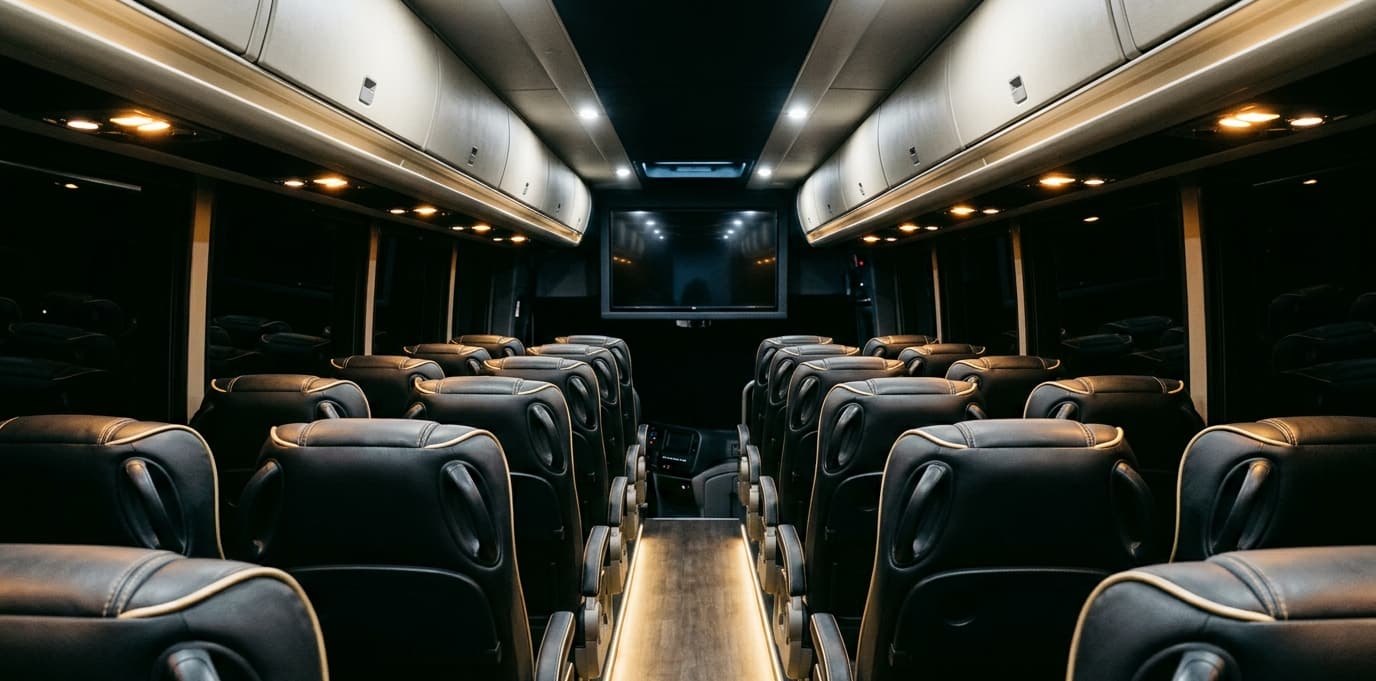 Coach Bus Deluxe interior — Aisle view — reclining seats with champagne piping, reading lights overhead.